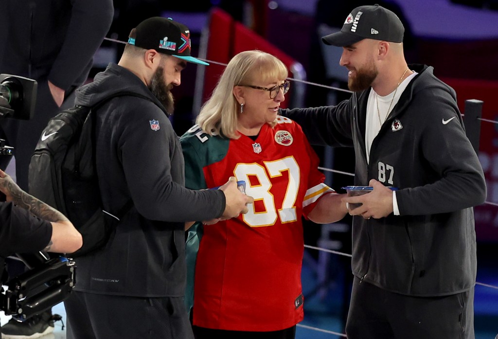 Donna Kelce (C) gives cookies to her son's Jason Kelce (L) #62 of the Philadelphia Eagles and Travis Kelce (R) #87 of the Kansas City Chiefs during Super Bowl LVII Opening Night at Footprint Center on February 6, 2023 in Phoenix, Arizona.  