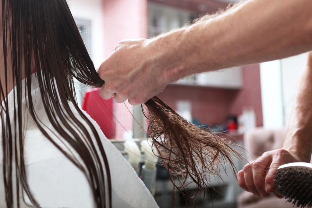A person in a beauty salon taking care of a woman's dark, tangled long hair