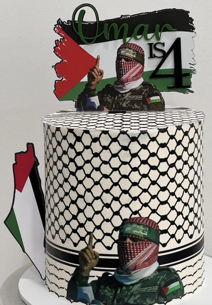 Four-year-old boy standing next to a large Hamas-themed birthday cake, decorated with a picture of Abu Ubaida and Palestinian flags