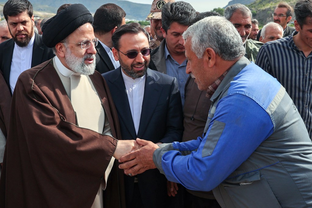 Iranian President Ebrahim Raisi shaking hands with officials at a proposed road and rail bridge project site near the Aras River, prior to his helicopter crash