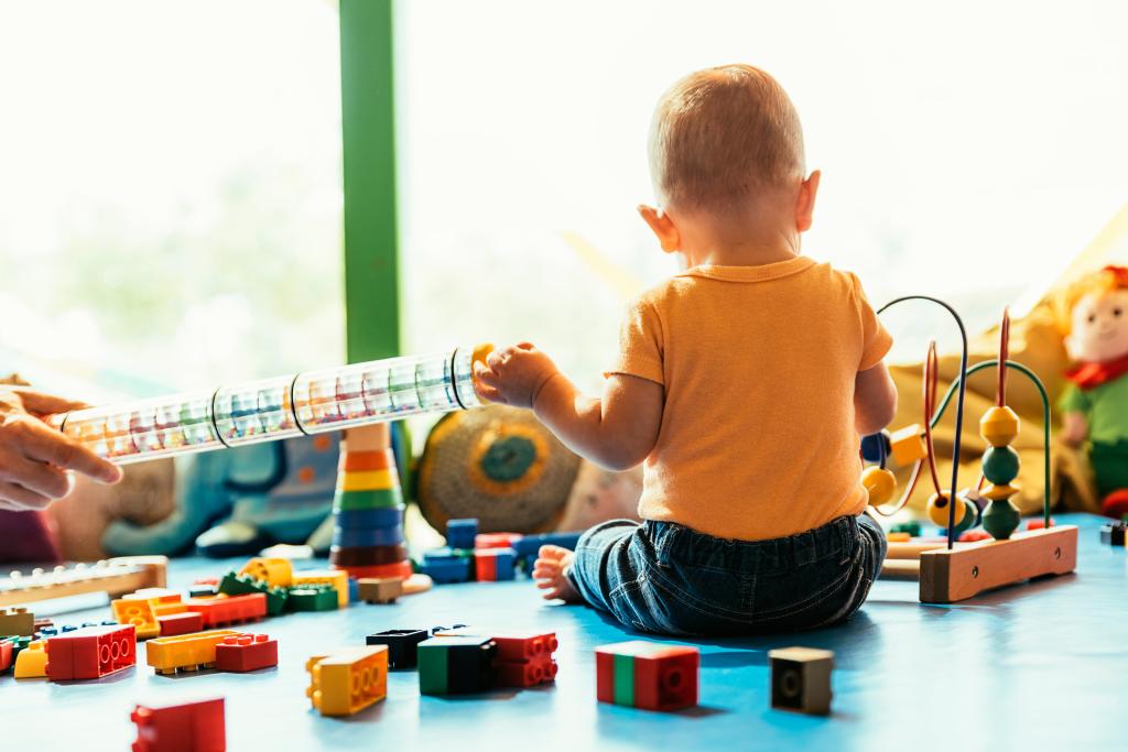 Happy baby playing with toy blocks in the kindergarten.