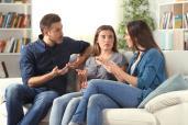 Three serious friends in conversation while sitting on a couch at home