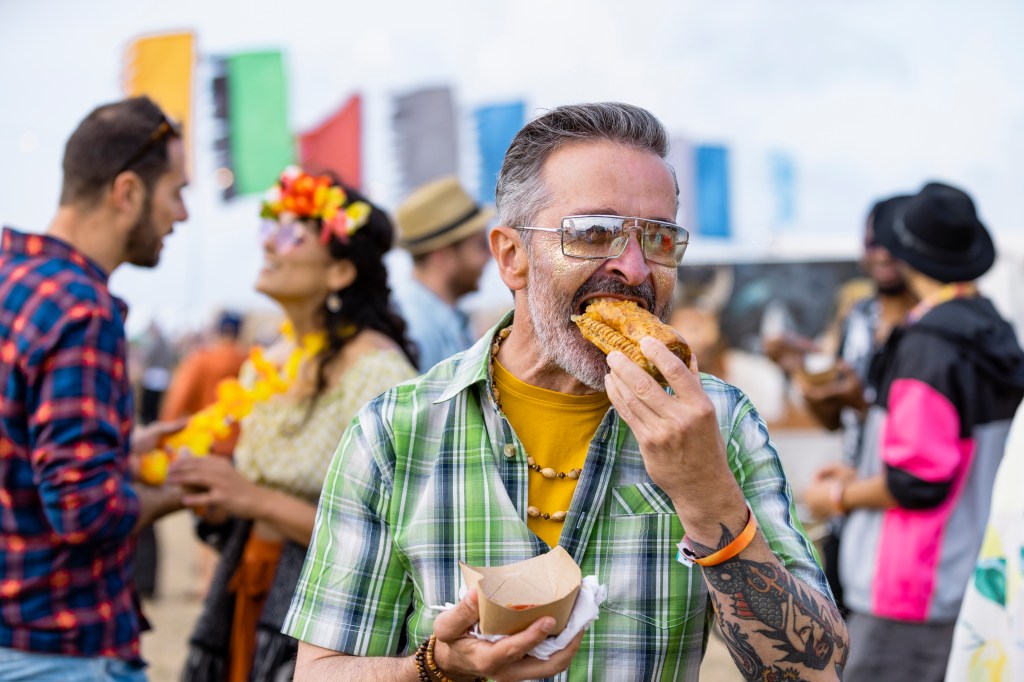 Group of mixed age and ethnic friends eating lunch they have bought from a food stall at a festival in Northumberland, North East England. 