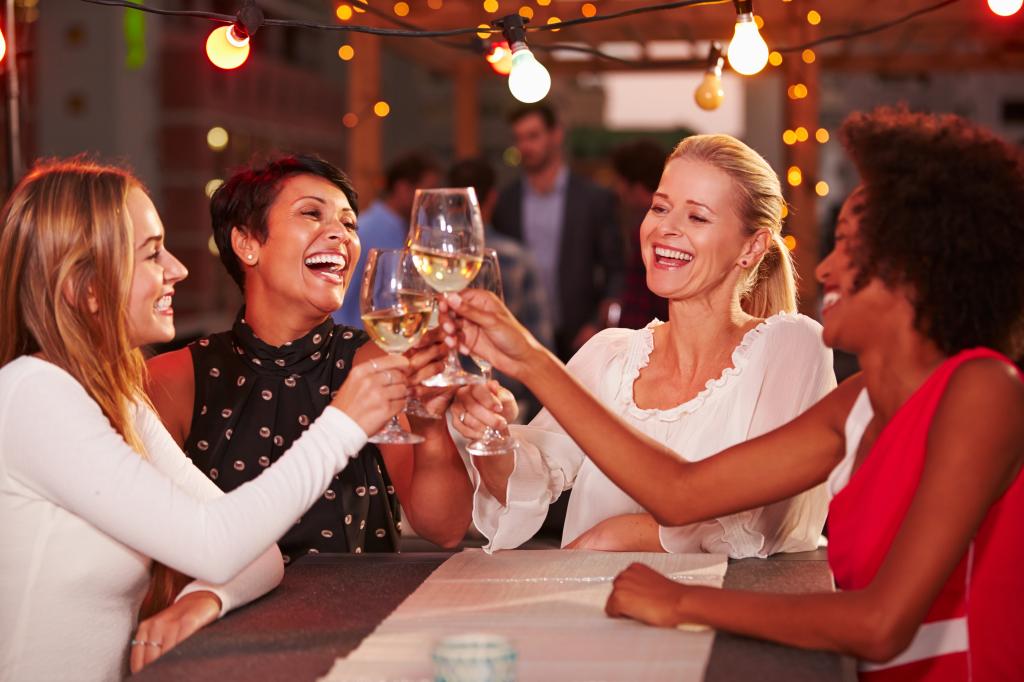 Girlfriends at rooftop party, holding up glasses of wine