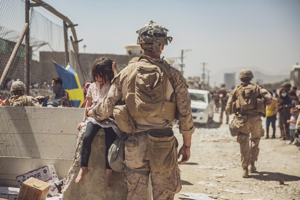 In this image provided by the U.S. Marine Corps, a Marine with Special Purpose Marine Air-Ground Task Force - Crisis Response - Central Command, takes care of a young girl awaiting processing at an evacuation control checkpoint during an evacuation at Hamid Karzai International Airport in Kabul, Afghanistan, Thursday, Aug. 26, 2021.