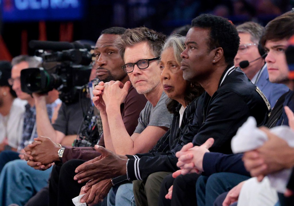 Actor Kevin Bacon sits on celebrity row between Leon Robinson and Chris Rock during the second quarter.