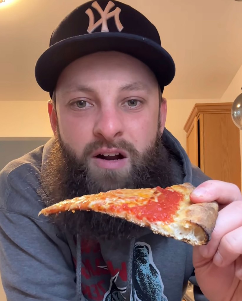 Bearded man enjoying a slice of pizza, living his passion for eating pizza daily for six years