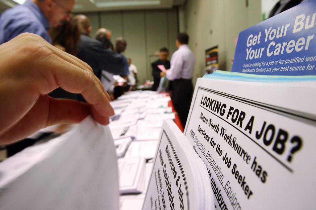 Job seekers looking at various job opening fliers at the Greater Los Angeles Career Expo at the Pasadena Convention Center