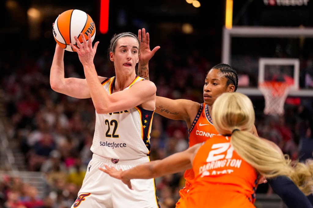 Indiana Fever guard Caitlin Clark (22) looks to pass over Connecticut Sun guard Tyasha Harris (52) and guard DiJonai Carrington (21) in the second half of a WNBA basketball game in Indianapolis, Monday, May 20, 2024.  