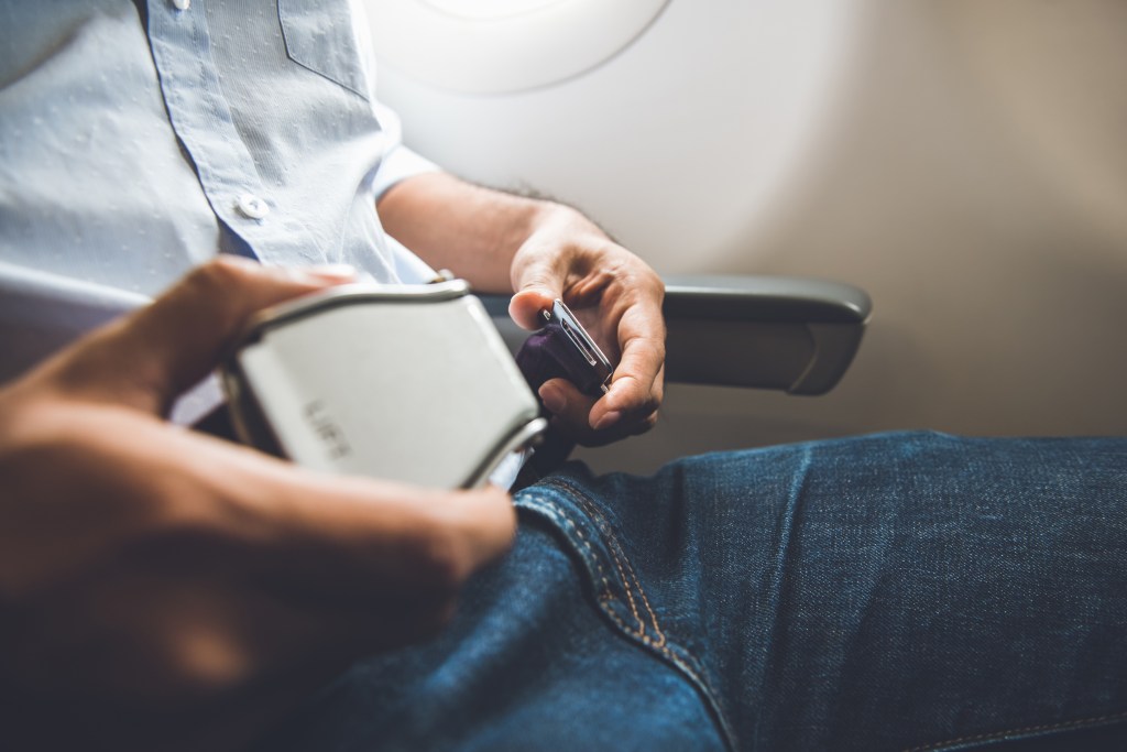 A plane passenger fastening their seatbelt.