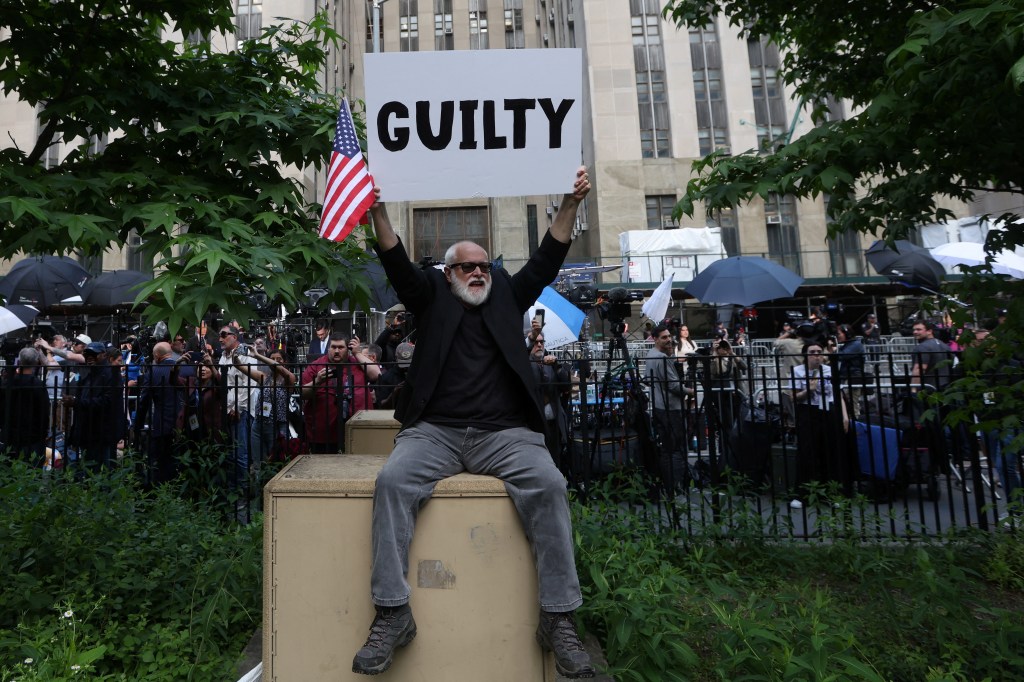 A man holds a placard outside Manhattan criminal court following the verdict in former U.S. President Donald Trump's criminal trial over charges that he falsified business records to conceal money paid to silence porn star Stormy Daniels.