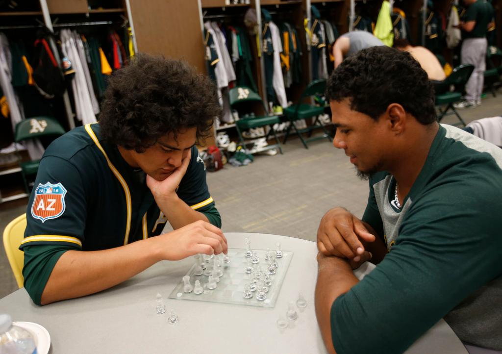 Sean Manaea #71 and Eduard Santos #75 of the Oakland Athletics play chess in the clubhouse during a spring training workout at Hohokam Stadium on March 3, 2016 in Mesa, Arizona.