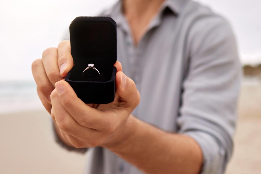 Man holding an open jewellery box with an engagement ring in it