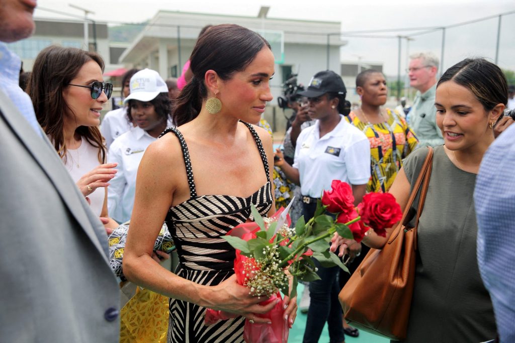 Meghan, Duchess of Sussex, holding flowers at a volleyball match with wounded army veterans in Abuja, Nigeria