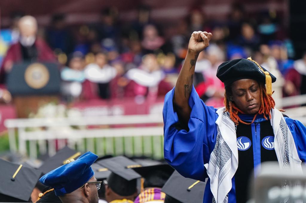 A Morehouse College faculty member in a blue robe standing and facing away from the stage in protest during President Joe Biden's commencement address