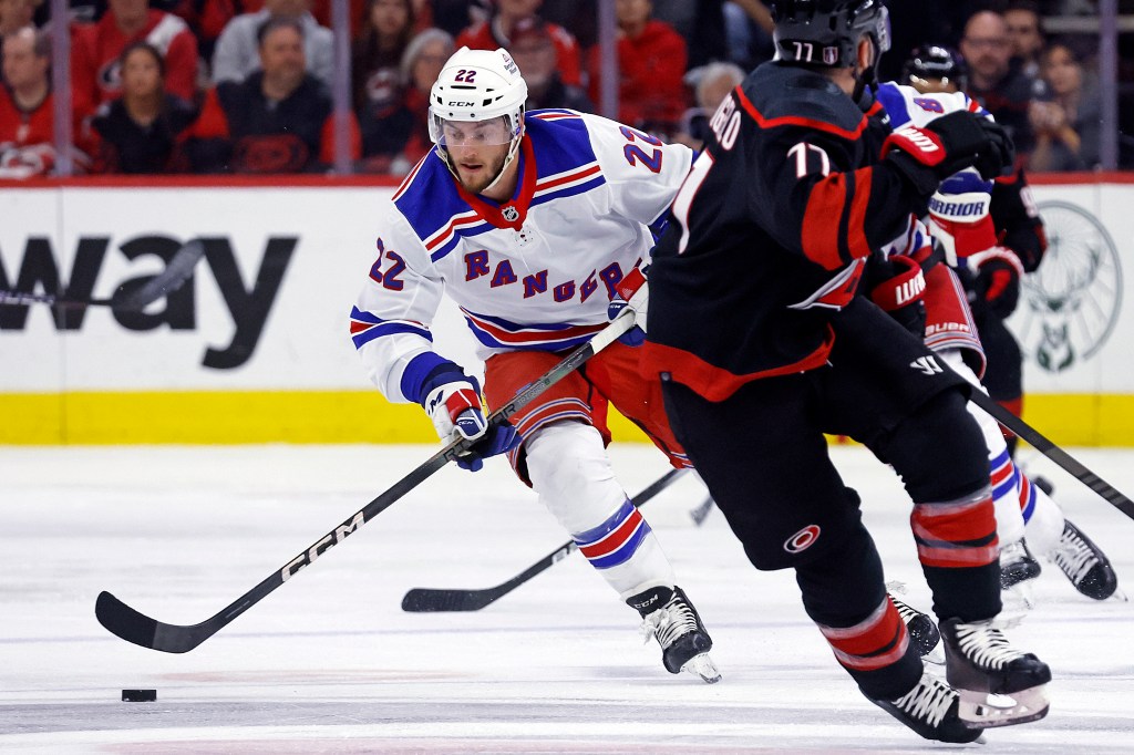 Rangers' Jonny Brodzinski (22) moves the puck around Carolina Hurricanes' Tony DeAngelo (77) during the first period in Game 6 of an NHL hockey Stanley Cup second-round playoff series in Raleigh, N.C.