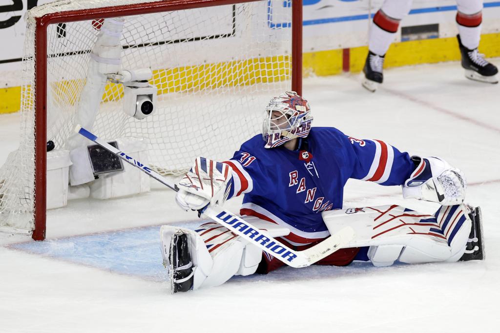 New York Rangers goaltender Igor Shesterkin in blue uniform, looking back at the puck in the net after a Carolina Hurricanes score during a NHL playoff game
