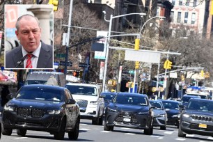 A man in a suit and tie walking on a street with cars