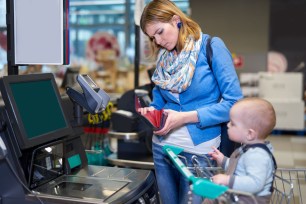 Woman with baby looking at grocery receipt