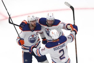 Connor McDavid (left) celebrates with teammates Zach Hyman (18) and Evan Bouchard (2) after scoring the game-winning goal in the Oilers' 3-2 double overtime win over the Stars in Game 1.