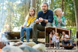 Father and two little girls roasting marshmallows at bonfire in a fall forest