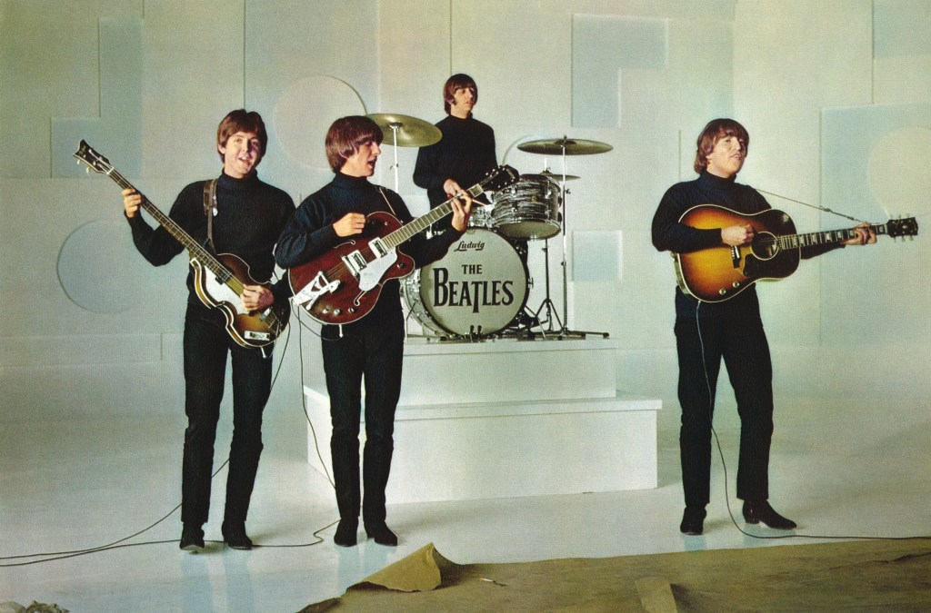 Paul McCartney, George Harrison, Ringo Starr, and John Lennon from The Beatles playing guitars in 1965