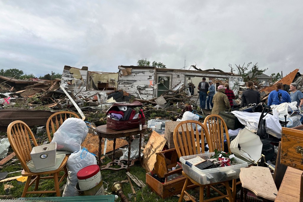 People examining and salvaging belongings from the damage caused by a tornado in Greenfield, Iowa, on May 21, 2024
