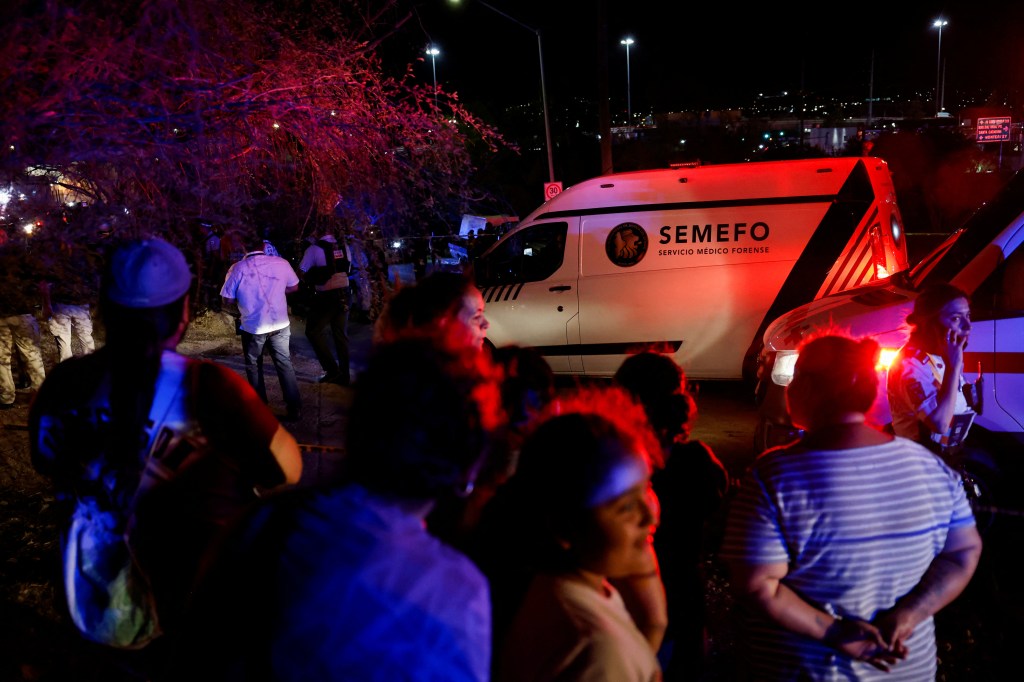 People look at a forensic service vehicle at the site after a gust of wind caused a structure to collapse on May 22, 2024.