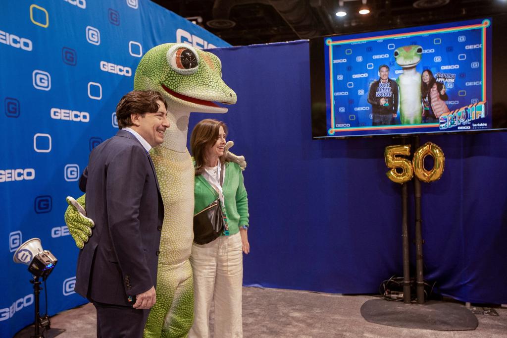 People posing with a 'gecko' mascot from GEICO at the Berkshire Hathaway event in Omaha, Nebraska