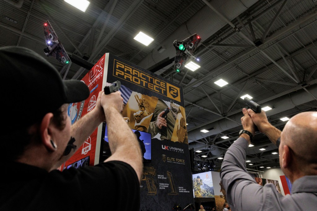 People practice their shot with laser technology at an exhibition booth during the annual National Rifle Association (NRA) meeting in Dallas, Texas, U.S., May 18, 2024