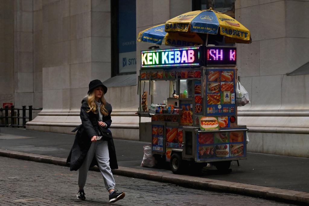 A person walks past a hot dog cart near the New York Stock Exchange (NYSE) in New York.