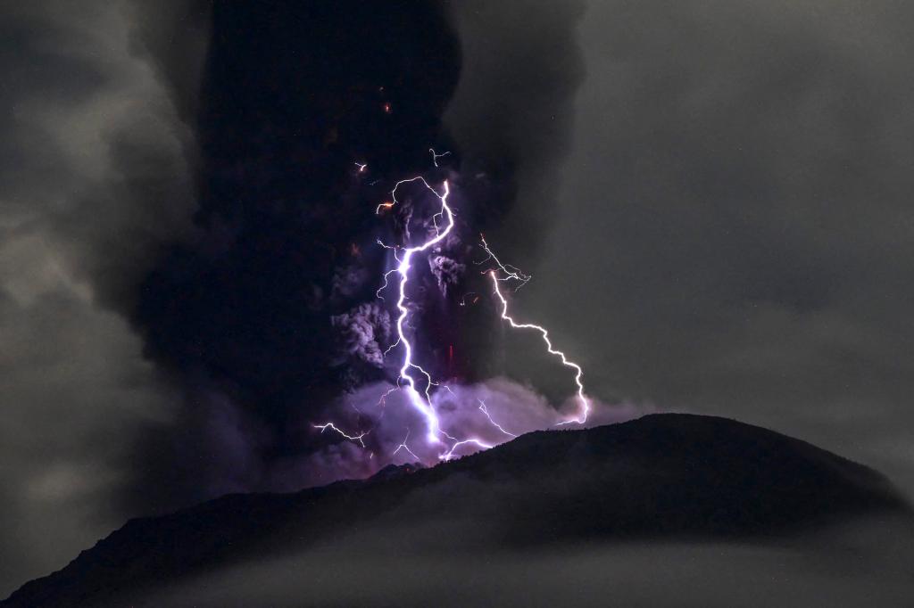 Mount Ibu in Indonesia spewing volcanic ash with lightning striking, as viewed from a distance, official warning issued to residents and tourists