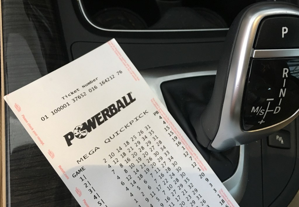 A paper with lottery numbers next to a car, representing Australia's Powerball lottery, TheLott