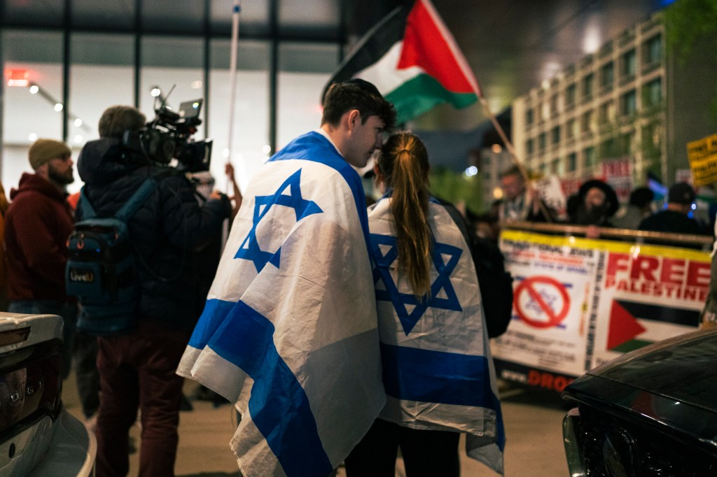 Pro Israel and pro Palestine protestors, including a man and woman with flags, clashing outside New York University on May 1, 2024