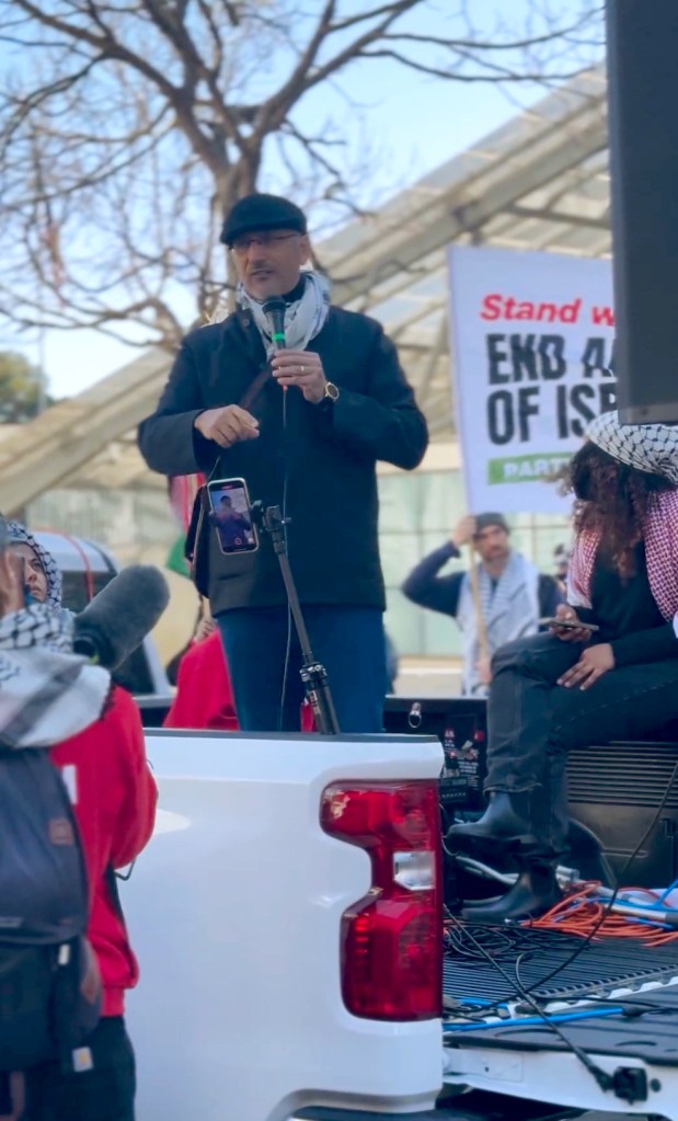 A man using the back of a pick-up as a platform to speak.