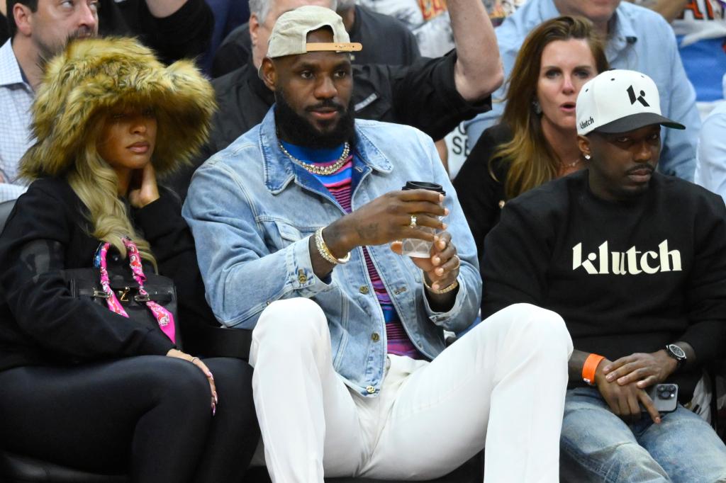LeBron James (c.) with wife Savannah (l.) and agent Rich paul (r.) sit courtside at the Cavaliers-Celtics playoff game in Cleveland Monday night.