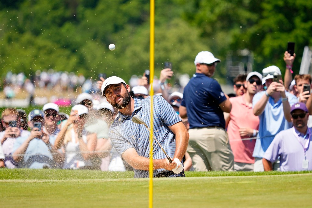  Scottie Scheffler plays a shot from a bunker on the first hole during the final round of the PGA Championship golf tournament.