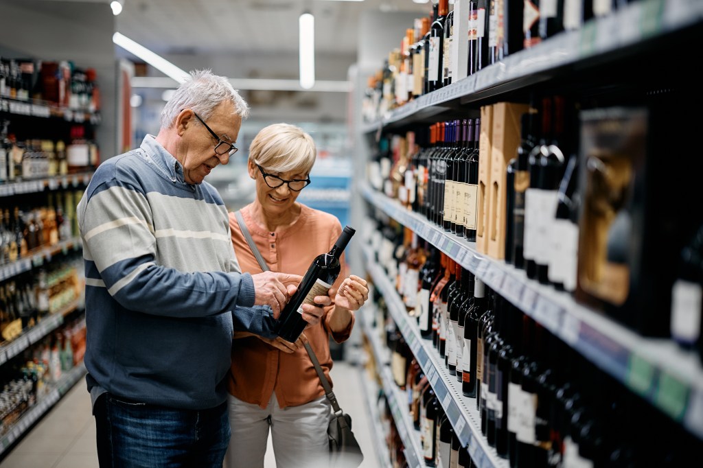 Senior man and his wife selecting a bottle of wine in a supermarket