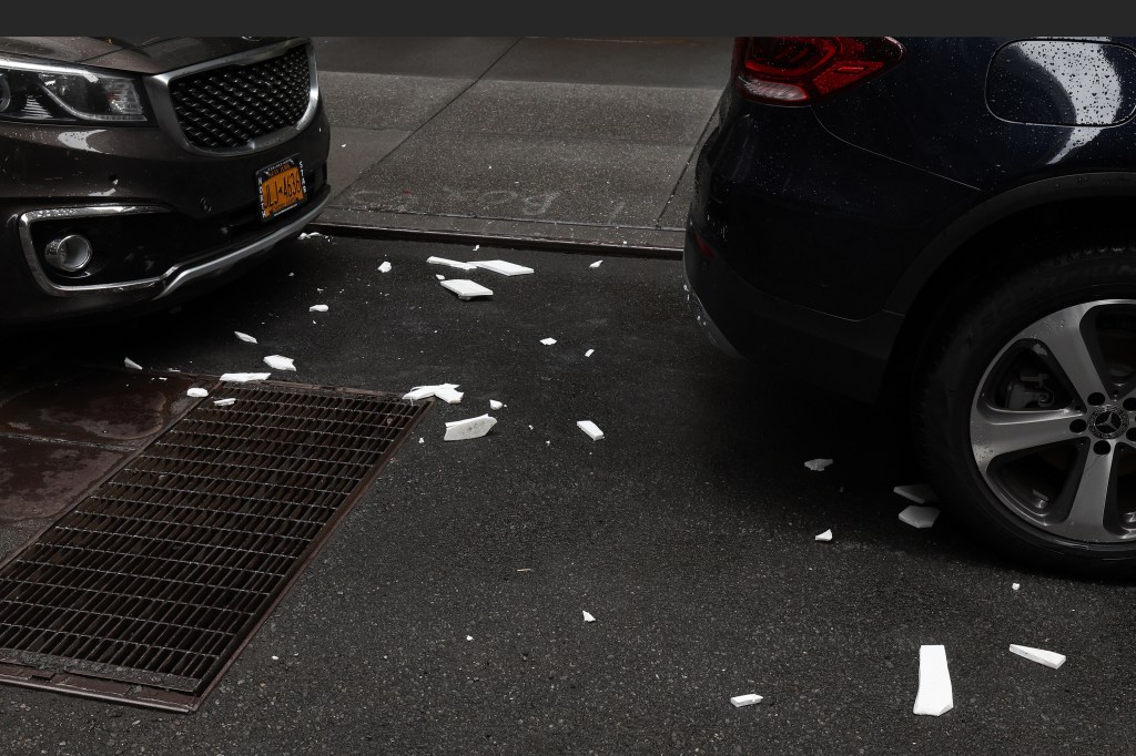 Broken tiles seen on the street near parked cars.