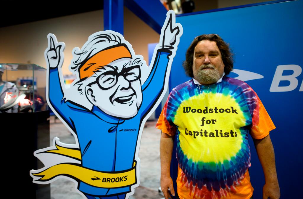 Shareholder holding a sign reading 'Woodstock for Capitalists' posing next to a stand-up image of Warren Buffett at Berkshire Hathaway's 2019 annual meeting