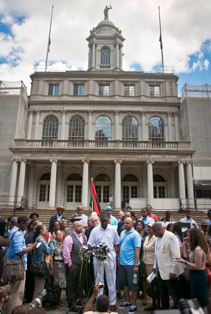 Surrounded by family and supporters, three of five men exonerated in the Central Park jogger rape case, Raymond Santana, center left, Yusef Salaam, center,  and Kevin Richardson, center right, stand before the microphones at a news conference in front of City Hall, Friday June 27, 2014 in New York. 