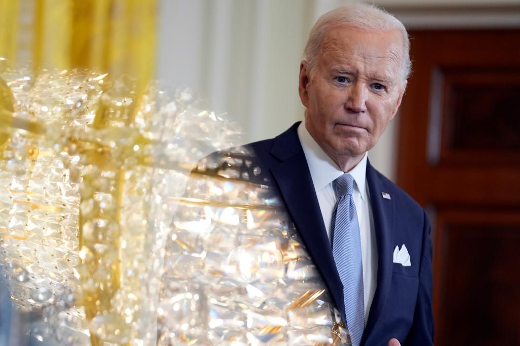 As a teleprompter screen reflects a chandelier light, President Joe Biden listens during a news conference with Kenya's President William Ruto in the East Room of the White House, Thursday, May 23, 2024, in Washington