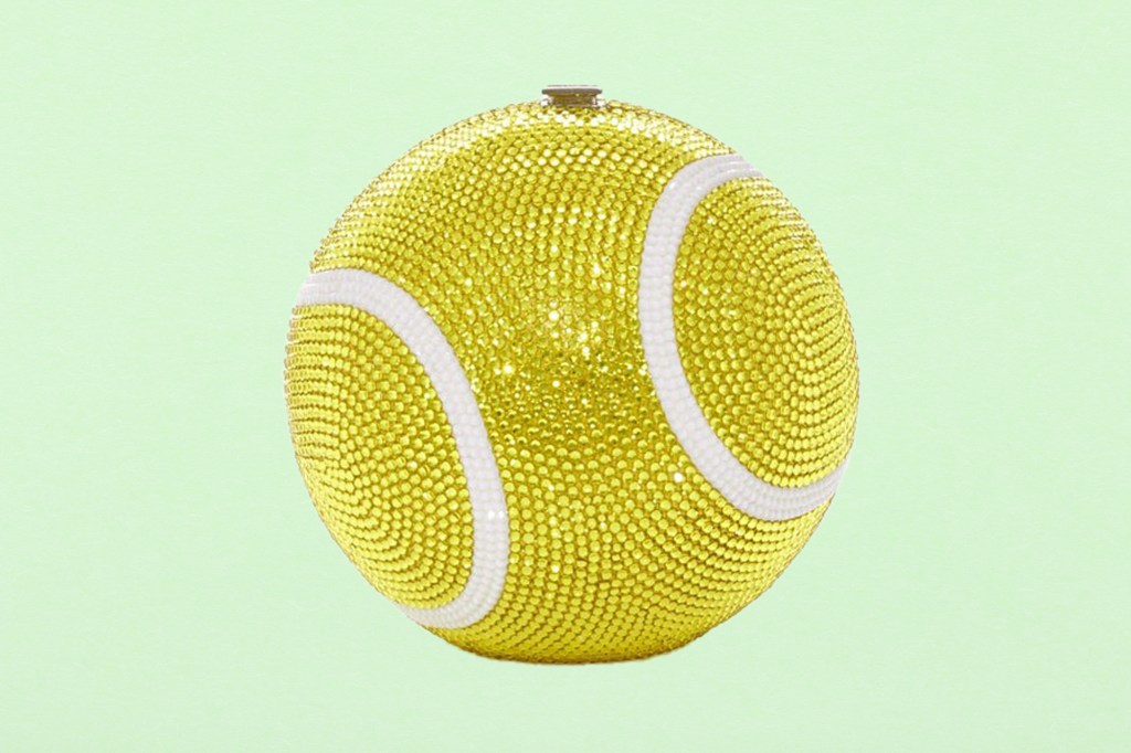Close-up view of a tennis ball made of rhinestones on a fresh green paper texture background