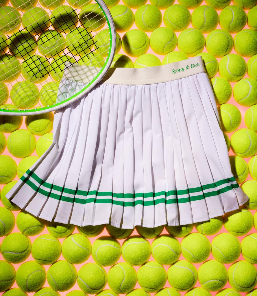 A tennis racket and skirt arranged on a tennis ball background
