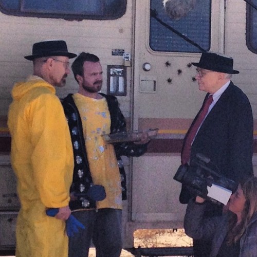 Warren Buffett with Bryan Cranston and Aaron Paul on the set of Breaking Bad, standing beside a train