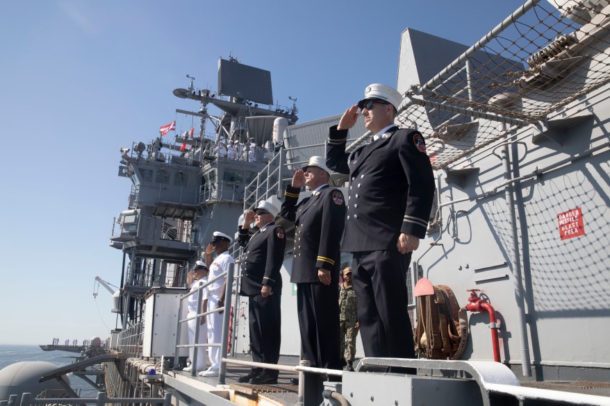 U.S. Navy Sailors assigned to the amphibious assault ship USS Bataan (LHD 5) and members of the New York City Fire Department man the rails as the ship pulls into New York City.