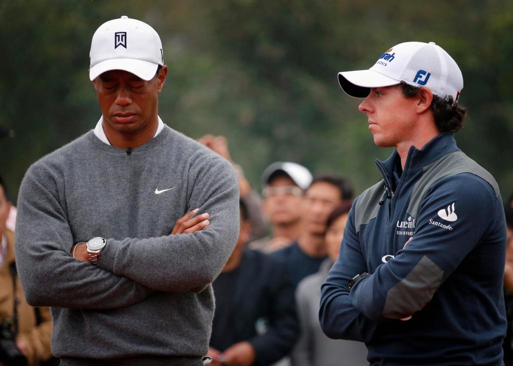 Tiger Woods reacting next to Rory McIlroy during trophy presentation at their exhibition event, Jinsha Lake Golf Club, with Woods crossing his arms.