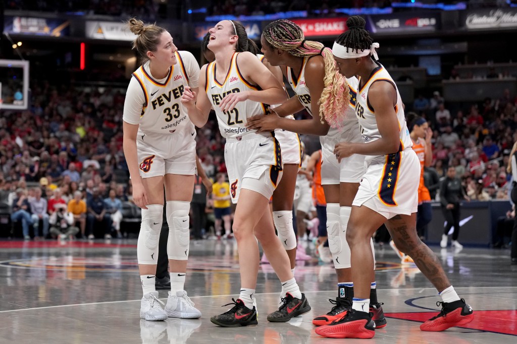 Teammates help Caitlin Clark #22 of the Indiana Fever off the court after an apparent injury during the second quarter