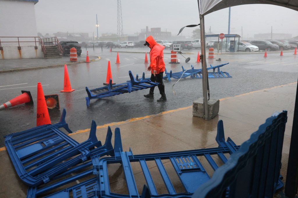 A worker attempting to collect barricades blown away by the storm at the Brooklyn Cruise Terminal on May 23, 2024.