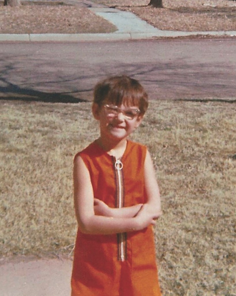 Demi Moore as a little girl in an ornage jumpsuit.